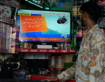 A shopkeeper watches a news channel airing news regarding people trapped in a cable car, at his shop in Lahore, Pakistan, Tuesday, Aug. 22, 2023. A cable car carrying six children and two adults dangled hundreds of meters (feet) above the ground in a remote part of Pakistan after it broke on Tuesday, trapping the occupants for hours before rescuers arrived in helicopters to try to free them.