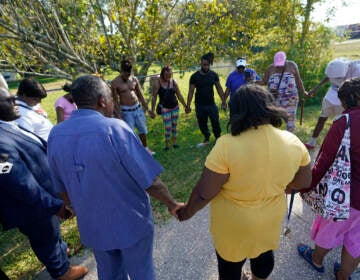 Residents gather for a prayer near the scene of a mass shooting at a Dollar General store, Saturday, Aug. 26, 2023, in Jacksonville, Fla. (AP Photo/John Raoux)