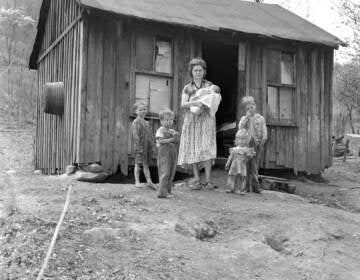 This is the home and family of Orville Sturgill, a United Mine Worker who is out of work due a strike in this coal field for higher wages in Mayking, Kentucky on April 28, 1959. Sturgill, with another miner, work a small truck mine but cannot market their production. This one room shack is on a county road running along Cram Creek. The five children, left to right are: Anderson, 6, Orville Ray, 5, Mrs. Cornia Mae Sturgill holds John, one month, Pricilla Ann, 2, and Arnold 8. Sturgill has a little garden patch in back of the house which he and the oldest son work. A sixth child is in Blind school in Louisville. (AP Photo/HBL)