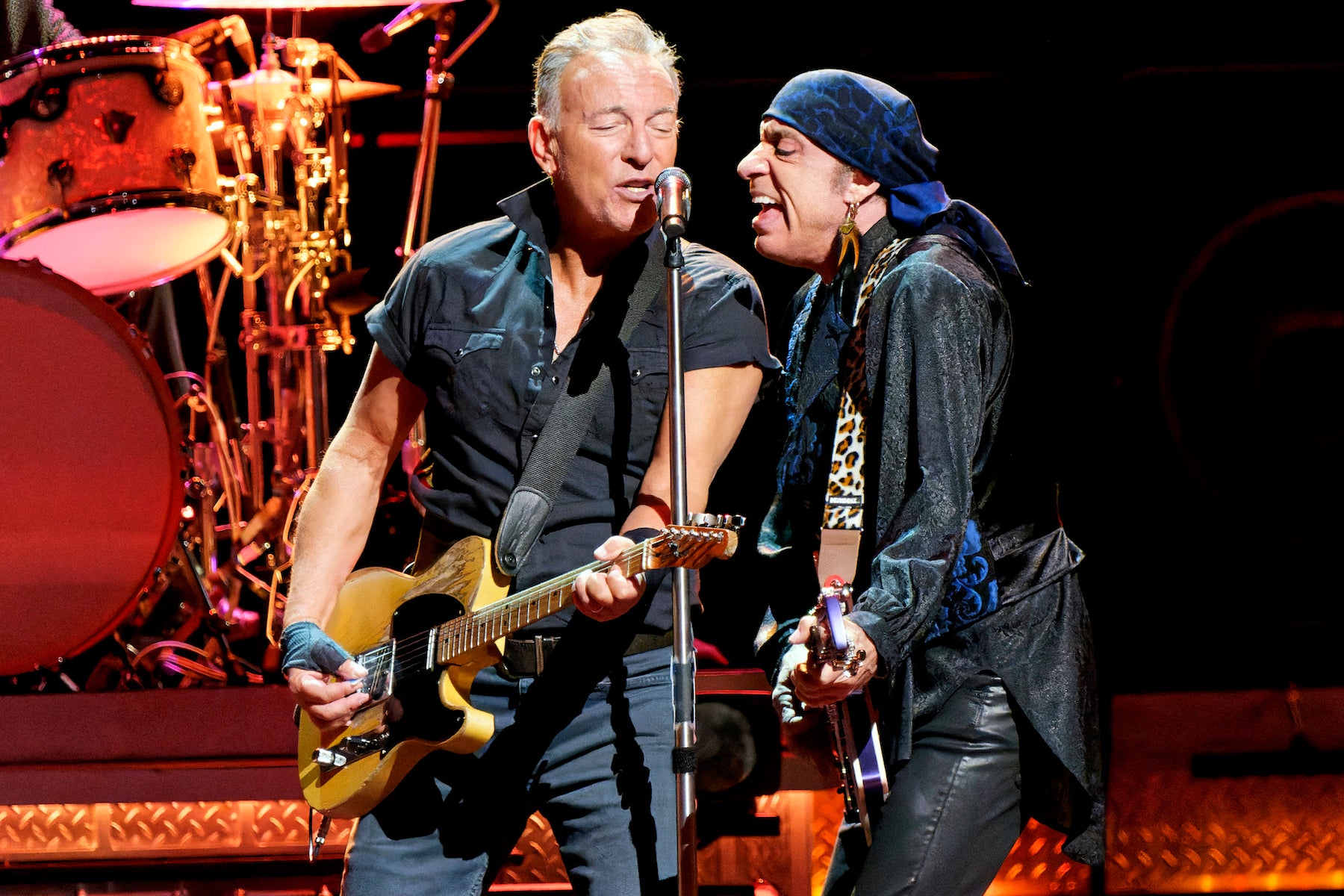 Bruce Springsteen and Steven Van Zandt singing into a microphone on stage