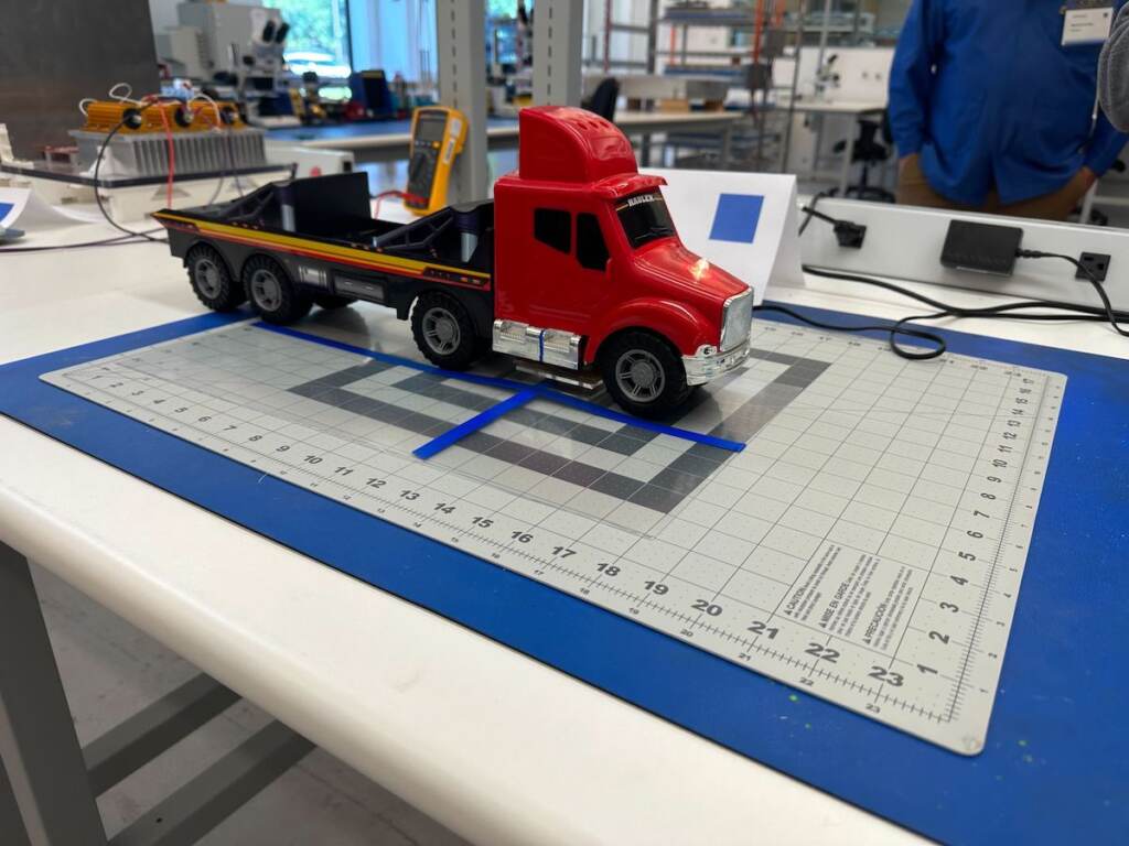 A model tractor trailer demonstrates charging technology in a lab.