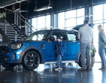 Potential buyers look at a 2023 Cooper Countryman S sports-utility vehicle on the floor of a Mini dealership on Friday, Feb. 17, 2023, in Highlands Ranch, Colo.