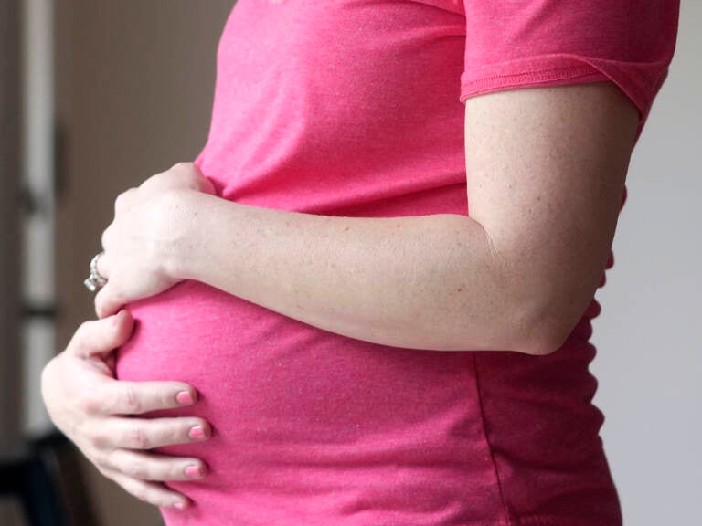 A pregnant woman holds her belly.