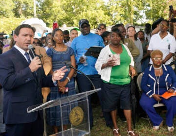 Florida Gov. Ron DeSantis, left, speaks at a prayer vigil on Sunday for the victims of a mass shooting that took place Saturday in Jacksonville, Fla.