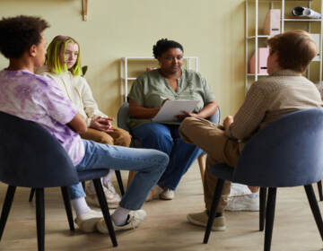 Female psychologist talking to teenagers during a therapy session. 