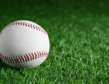 A baseball is visible on the grass
