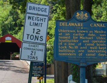 A sign about the history of Uhlerstown sits at the entrance of the bridge. (Gina E. Kim/WHYY)