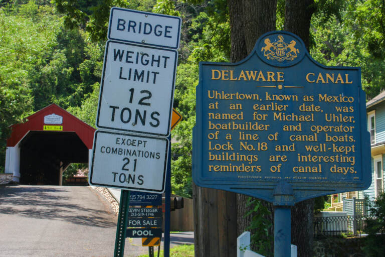 A sign about the history of Uhlerstown sits at the entrance of the bridge. (Gina E. Kim/WHYY)