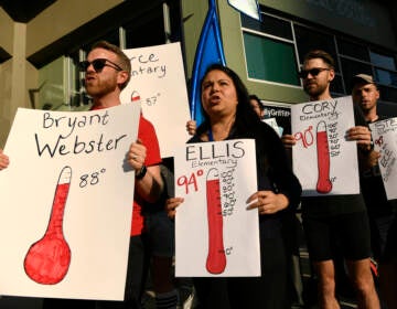 Protesters hold up signs outside of the Denver Public Schools administration building to demand equity for students attending classes in excessively hot classrooms.