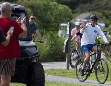 President Biden waves to onlookers as he rides his bike through Gordons Pond State Park in Rehoboth Beach, Del., on Tuesday.