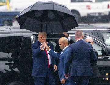 Trump holding an umbrella in the rain