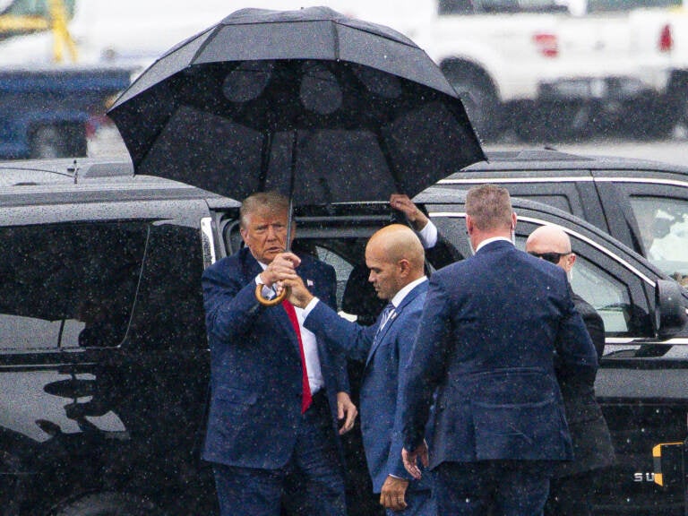 Trump holding an umbrella in the rain