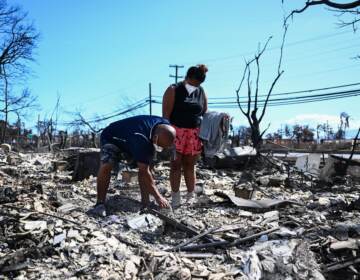 Davilynn Severson and Hano Ganer look for belongings through the ashes of their family's home on Friday in the aftermath of a wildfire in Lahaina, in western Maui, Hawaii.