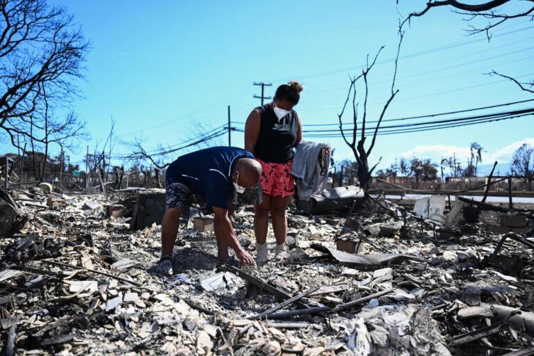 Davilynn Severson and Hano Ganer look for belongings through the ashes of their family's home on Friday in the aftermath of a wildfire in Lahaina, in western Maui, Hawaii.