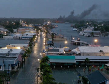 In an aerial view, a fire is seen as flood waters inundate the downtown area after Hurricane Idalia passed offshore Wednesday in Tarpon Springs, Fla.