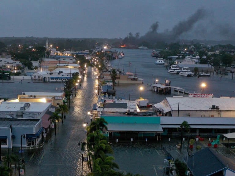 In an aerial view, a fire is seen as flood waters inundate the downtown area after Hurricane Idalia passed offshore Wednesday in Tarpon Springs, Fla.