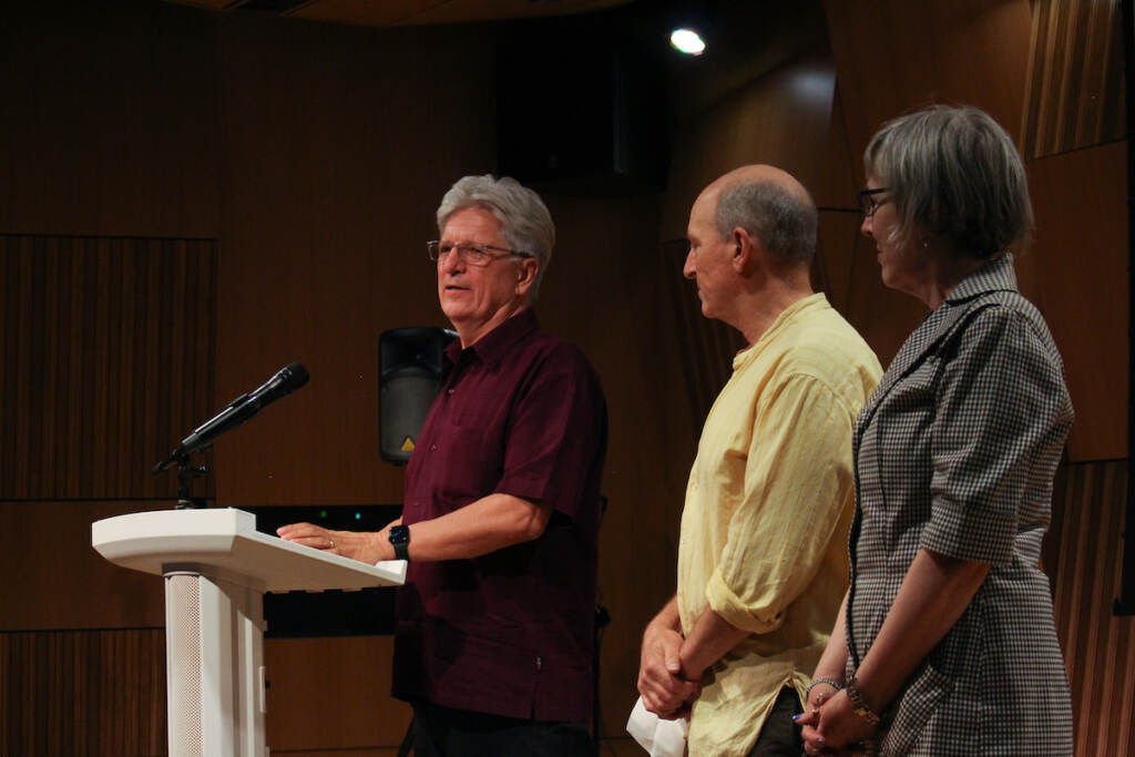 Tony Heriza, Jim Wasserman, and Val Keller stand onstage.