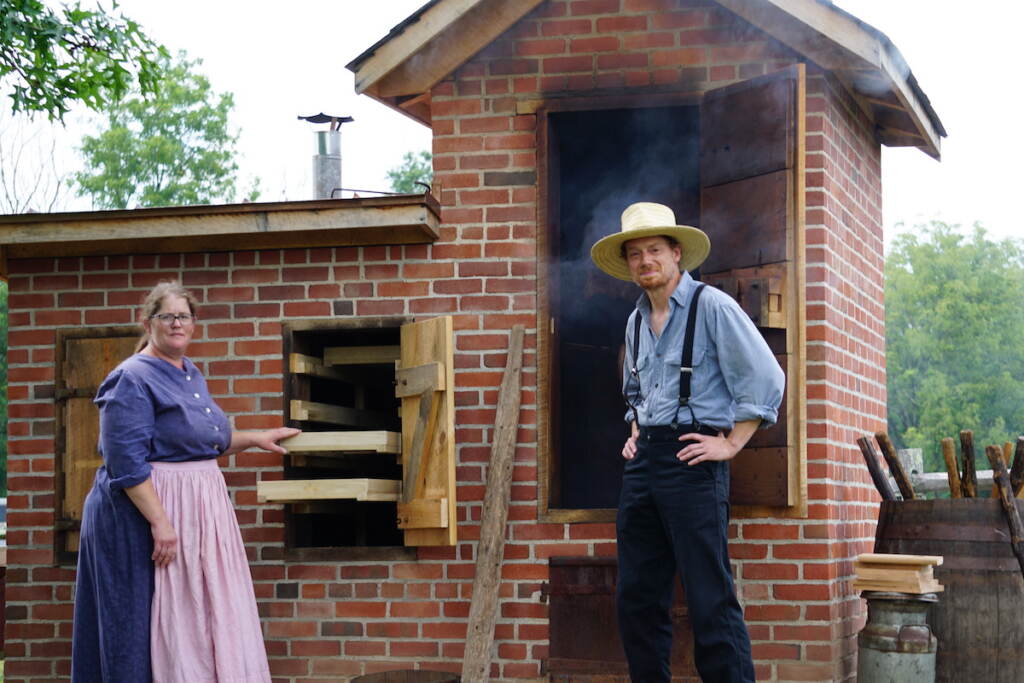 Rachel Anders and Lee Basset pose for a photo near the "smoker" where food is smoked to preserve it