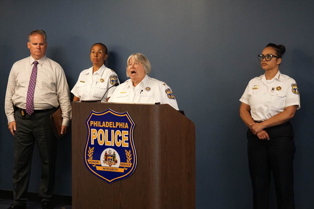 Christine Coulter speaking at a podium with other police officials