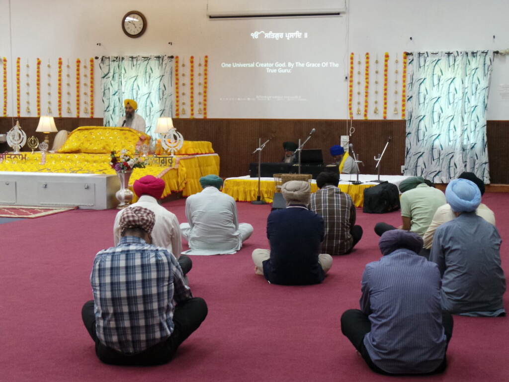 Community members sit and listen at a gurdwara