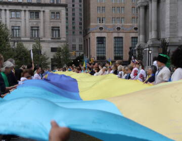 Attendees hold a huge Ukrainian flag outside of City Hall.