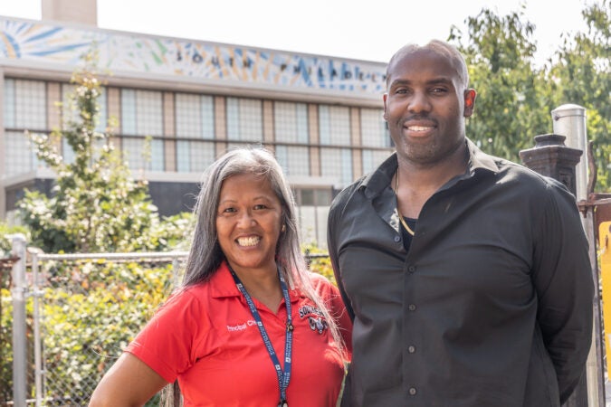 South Philadelphia High School principal Kimlime Chek-Taylor (left) and 10th grade Dean and English teacher Armond James, outside the school after heat in the city prompted the district to dismiss students at 74 schools that don’t have air conditioning on the first day of school, September 5, 2023. (Kimberly Paynter/WHYY)