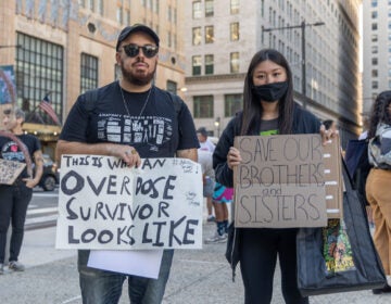 Protesters hold signs advocating for supervised injection sites.