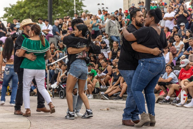 Attendees dance together in pairs as a crowd looks on.