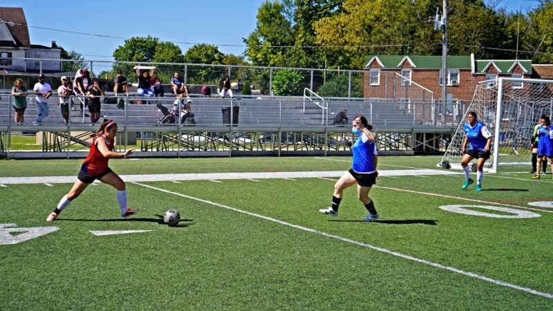 Players run towards a soccer ball