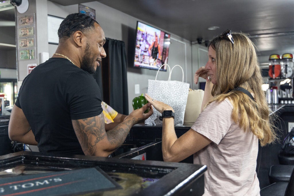 Kerry Wilson (right) shares homegrown produce with Big Tom’s Tavern owner Thomas Jackson (left).