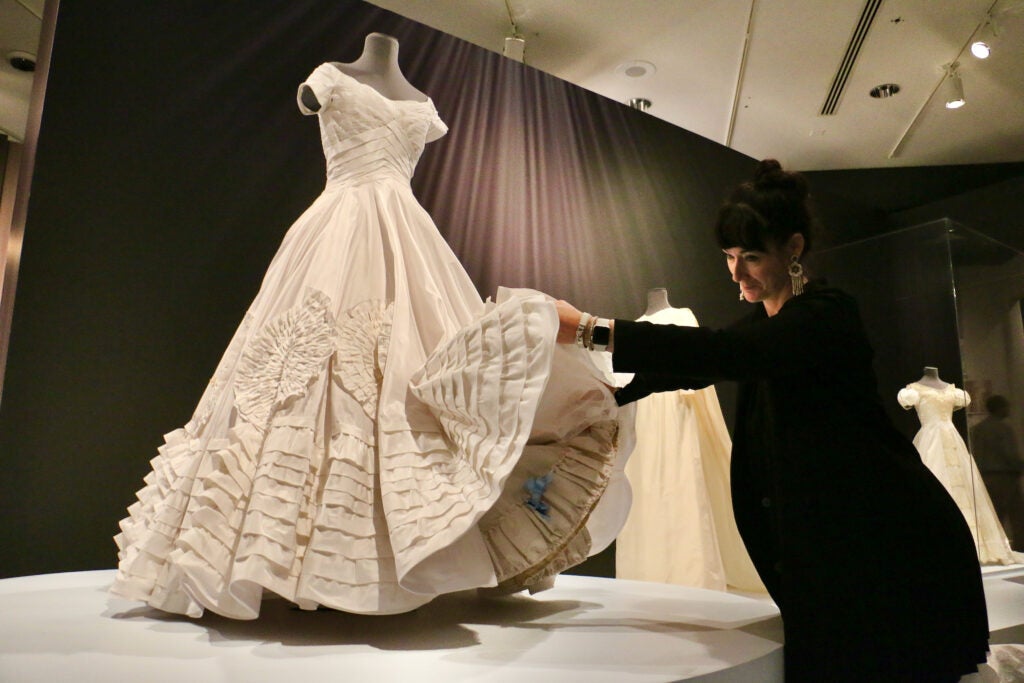 Katya Roelse lifts the skirt of the replica of Jacqueline Kennedy's wedding dress that she created to reveal a blue ribbon