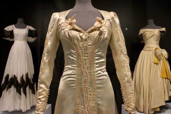 An elaborate dress in the foreground and two other dresses visible in the background.