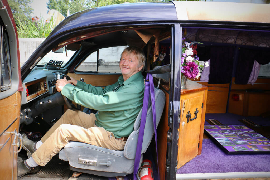 Bill Doran, the superintendent of Laurel Hill Cemetery, poses for a photo while in the driver's seat of a purple hearse