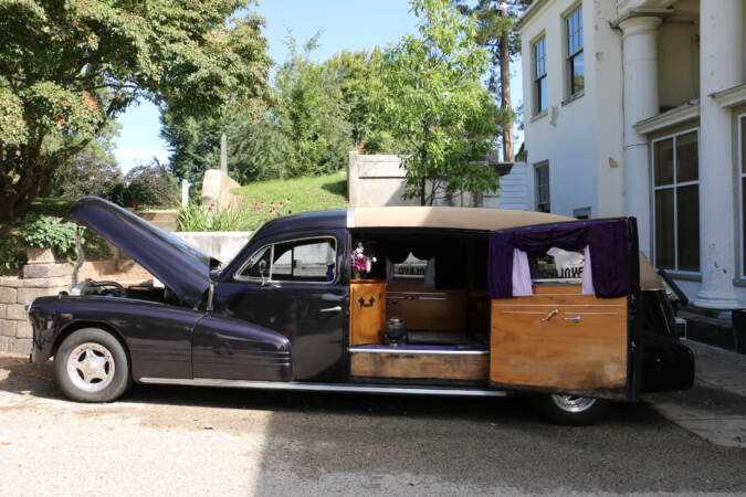 A purple hearse is visible