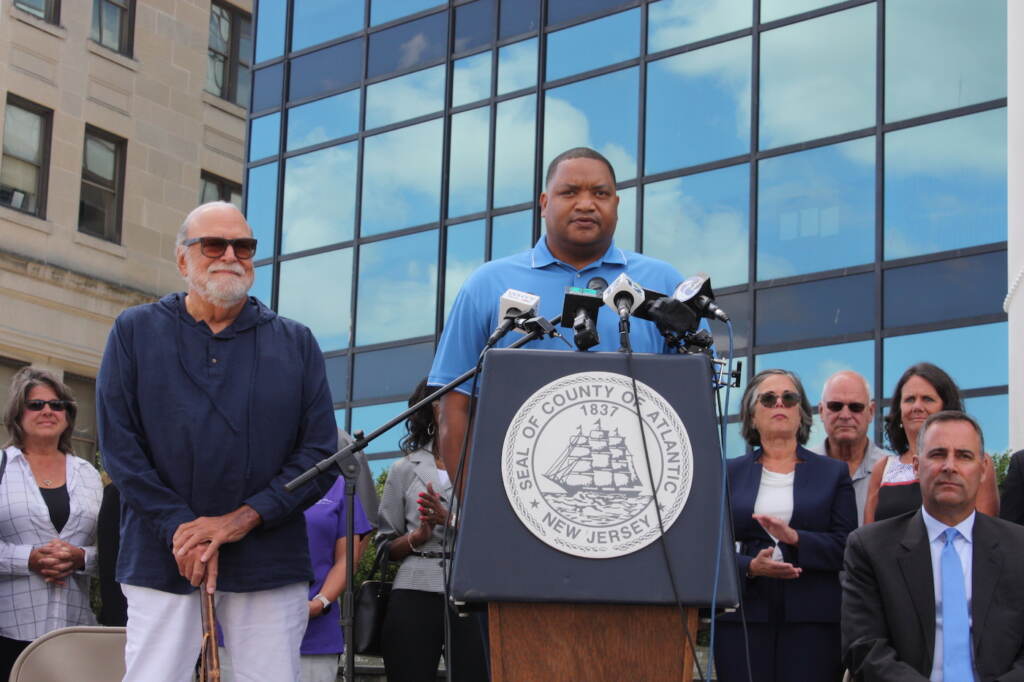 Marty Small speaking at a podium, with other officials