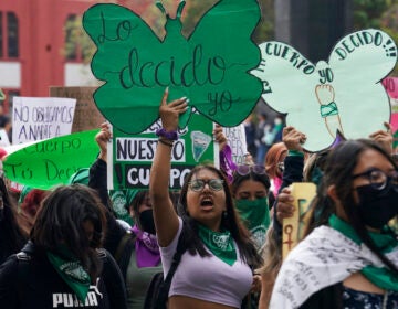 A woman holds up a sign with a message that reads in Spanish; 