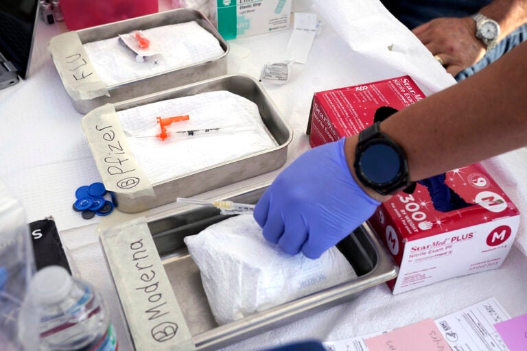 Syringes with vaccines are prepared at the L.A. Care and Blue Shield of California Promise Health Plans' Community Resource Center where they were offering members and the public free flu and COVID-19 vaccines Oct. 28, 2022, in Lynwood, Calif. Updated COVID-19 vaccines in the latter half of 2023 come just in time to pair them with flu shots. (AP Photo/Mark J. Terrill, File)