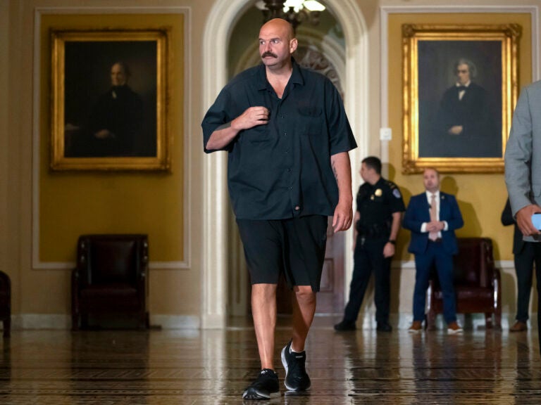 Sen. John Fetterman, D-Pa., walks on Capitol Hill on Thursday. He says he will continue to wear a suit on the Senate floor in compliance with the newly codified dress code. Mark Schiefelbein/AP