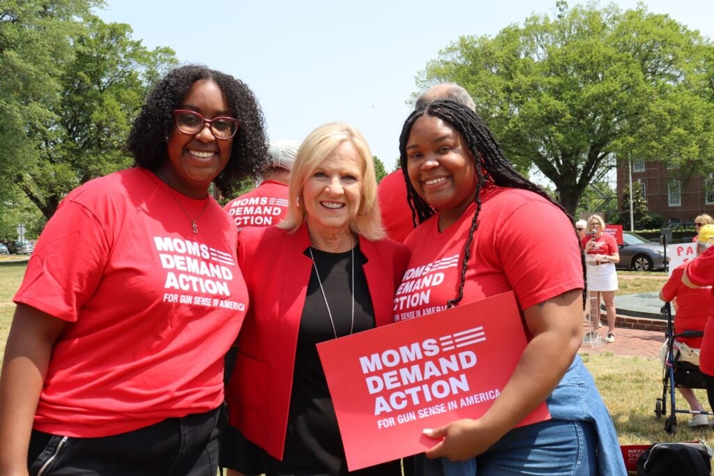 Bethany Hall-Long posing for a photo with 2 women wearing 'Moms Demand Action' shirts