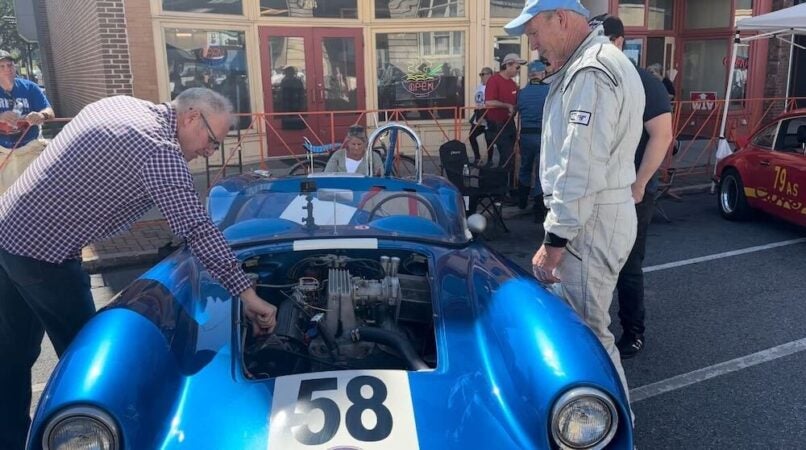 Racers check the engine of a blue vintage car