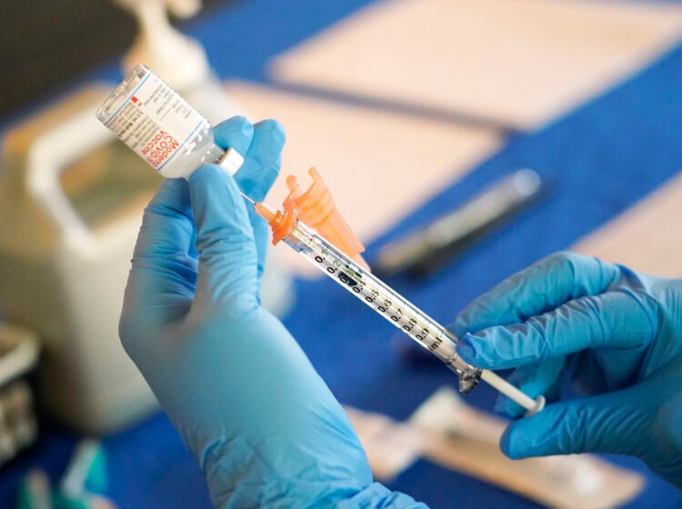 A medical professional prepares a vaccine syringe.