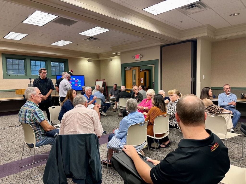 People sit in chairs at a town hall meeting.