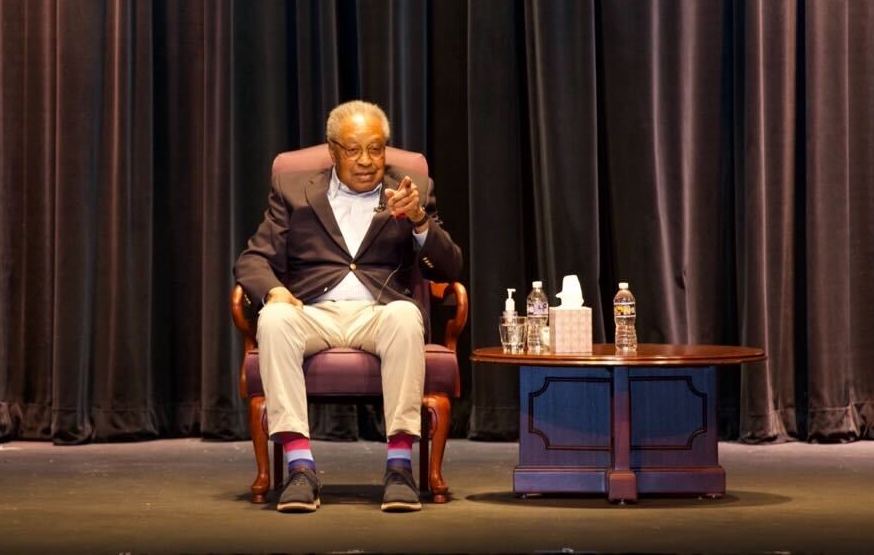 Dr. Clarence B. Jones is seen sitting on a stage at Camden County College