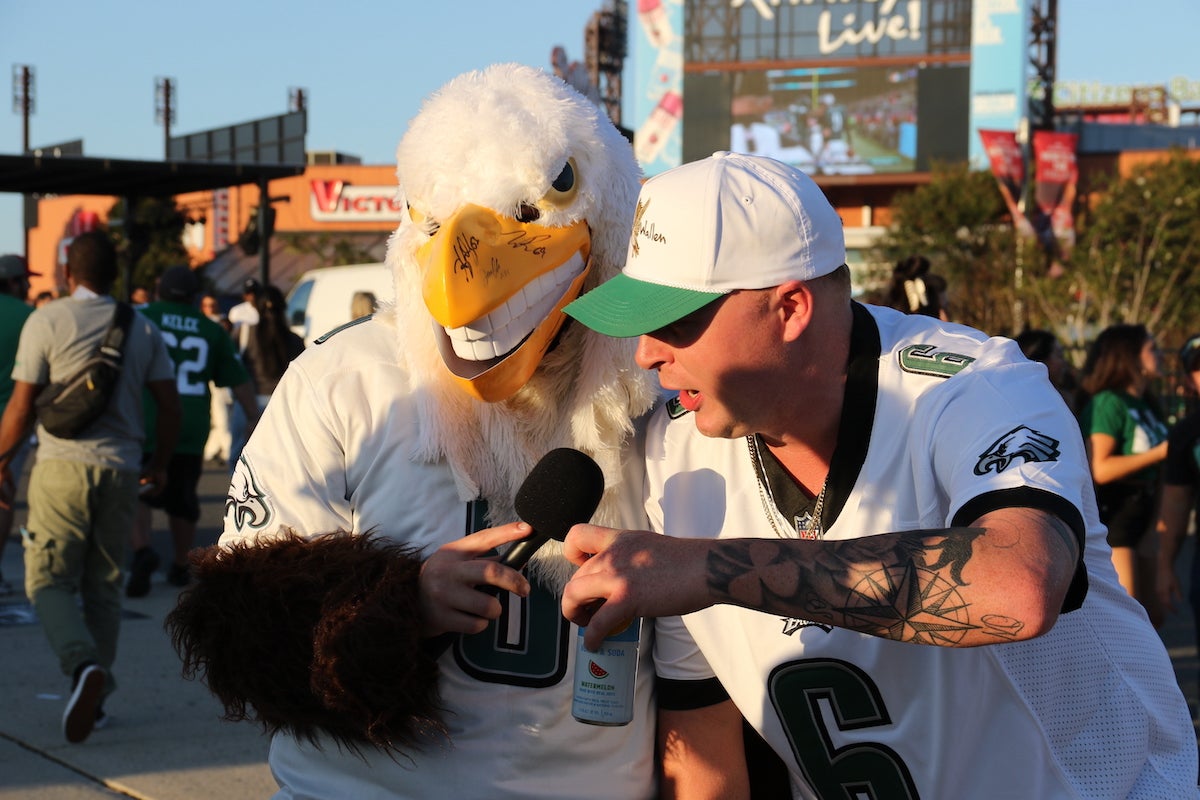 A fan talks with someone dressed in an Eagles mascot outfit.
