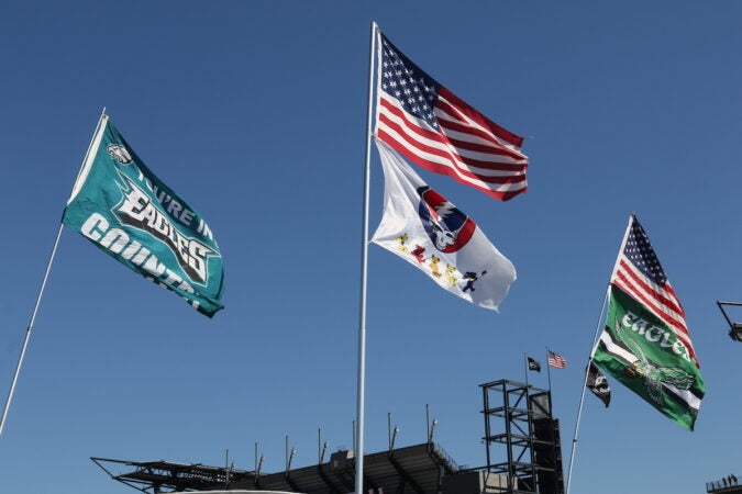 Flags fly in the wind, including the U.S. flag and Eagles flags.