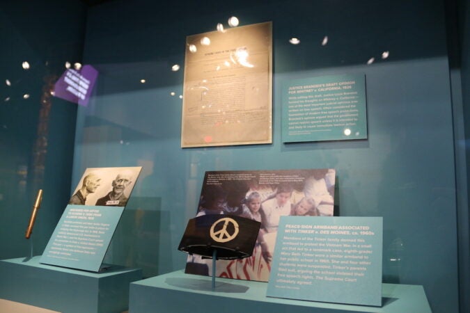 Objects, photos, and texts are displayed in a display case.