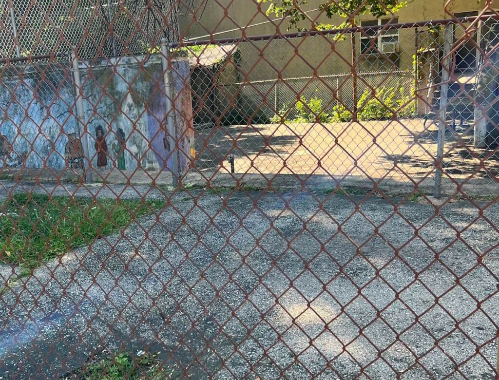 A vacant lot shown behind a fence