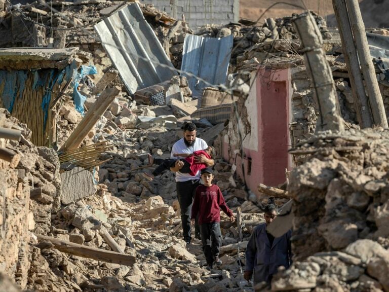 People walk past destroyed houses after an earthquake in the mountain village of Tafeghaghte, southwest of the city of Marrakech, on Saturday.