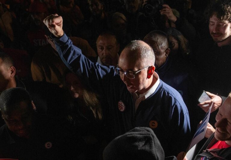 Shawn Fain raising his fist in a crowd of people.