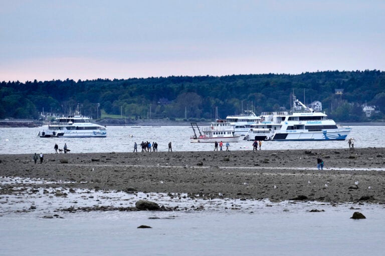 Visitors walk along a sand bar at low tide in advance of Hurricane Lee, Friday, Sept. 15, 2023, in Bar Harbor, Maine.